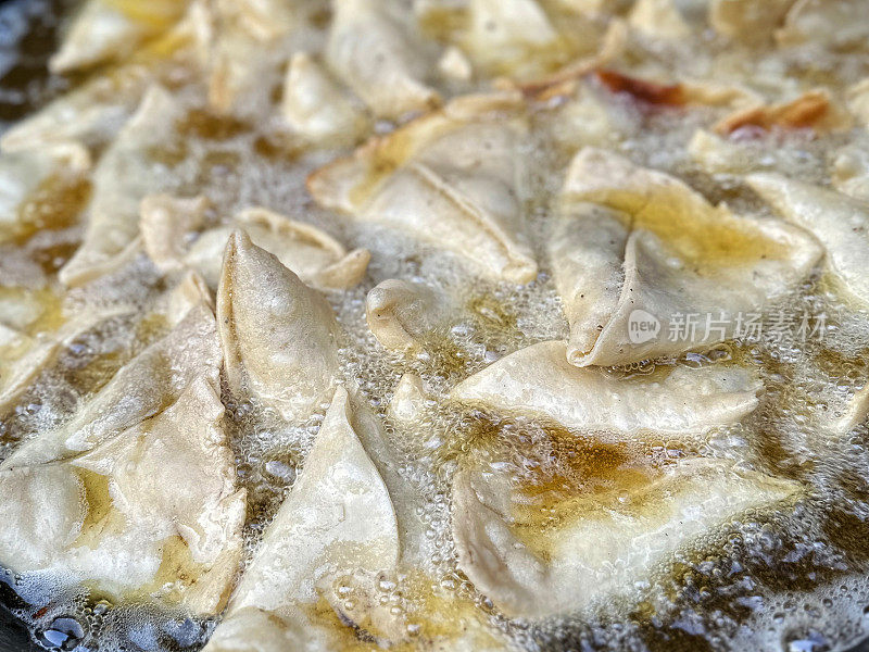 全帧图像的samosas在karahi(印度锅)中油炸，冒泡的热油，印度街头小吃摊，不健康的饮食，高架视图