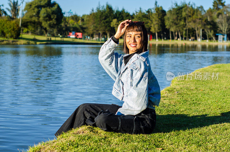 在一个阳光明媚的日子里，一名剪短头发的年轻女子在公园里穿着休闲服，戴着太阳镜