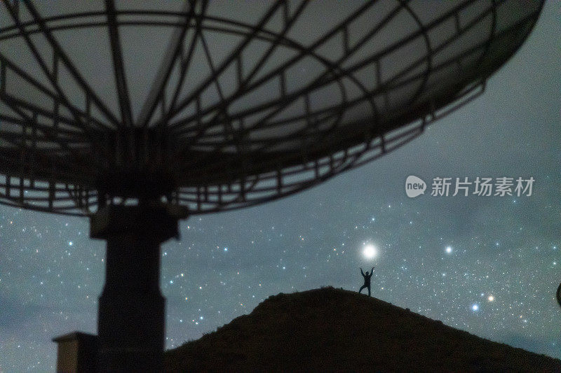 人们在卫星天线旁仰望星空