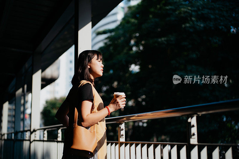 亚洲女人在城市里喝外带咖啡