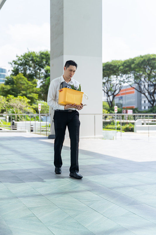 一名中国男子在被裁员后拿着自己的行李