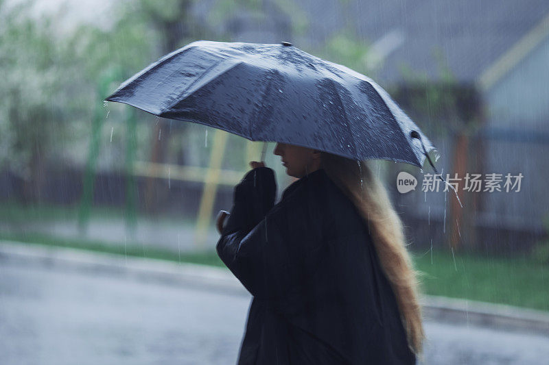 伞下的金发女人。暴风雨天气。暴雨