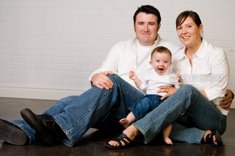一张穿着蓝色牛仔裤的爸爸、妈妈和蹒跚学步的孩子的全家福