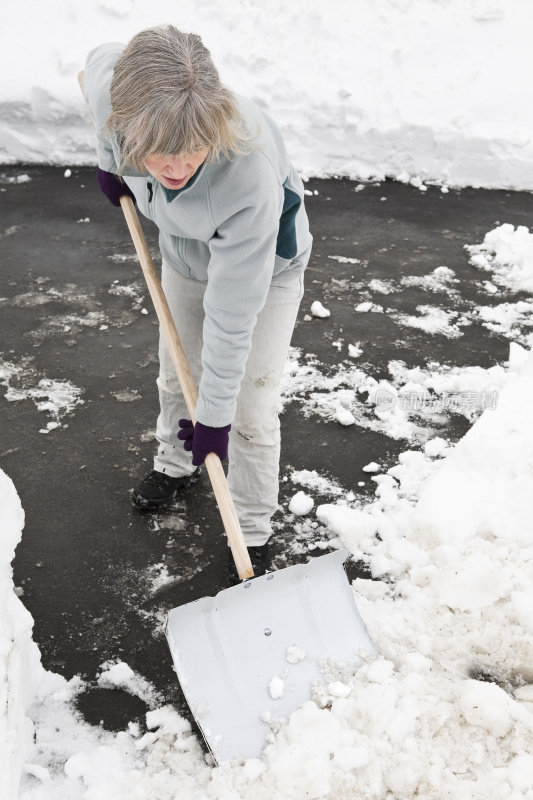 用大铲铲雪的女人。