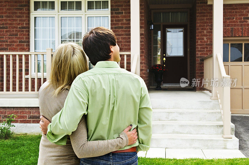 一对幸福的夫妇在房子前拥抱