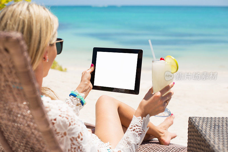 轻松的女人在海滩上使用平板电脑