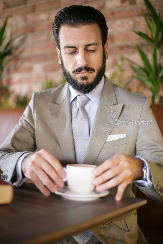 年轻的大胡子男人在喝咖啡