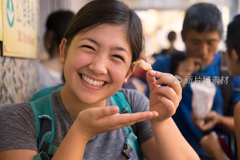 微笑的年轻女子拿着在街头市场买的炸蟹
