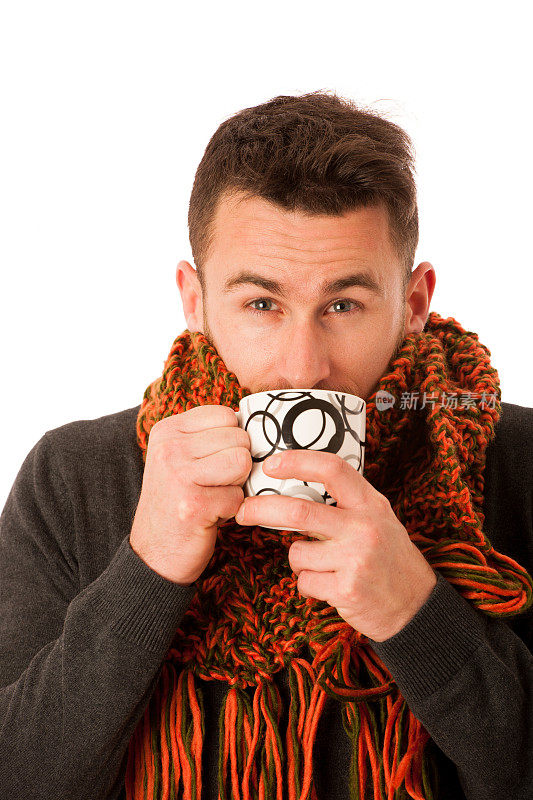 一个患流感和发烧的人裹着围巾，拿着杯子