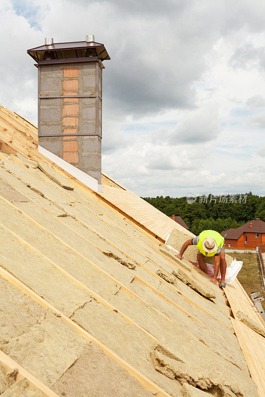 屋顶建筑工在新房子上安装屋顶保温材料