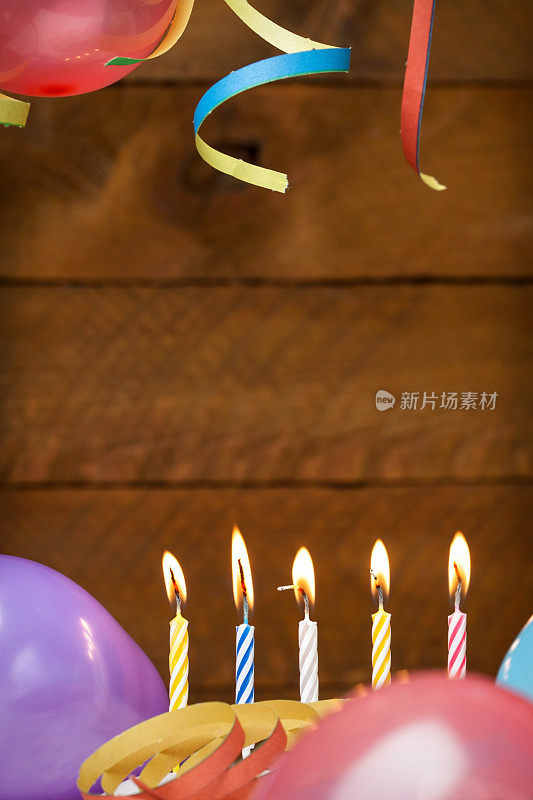 气球，蜡烛和彩带的木制背景