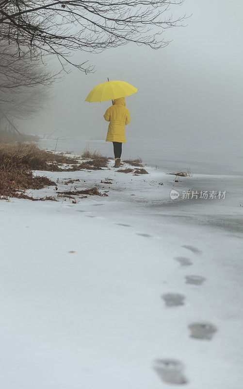 穿着黄色外套的少女在湖边散步