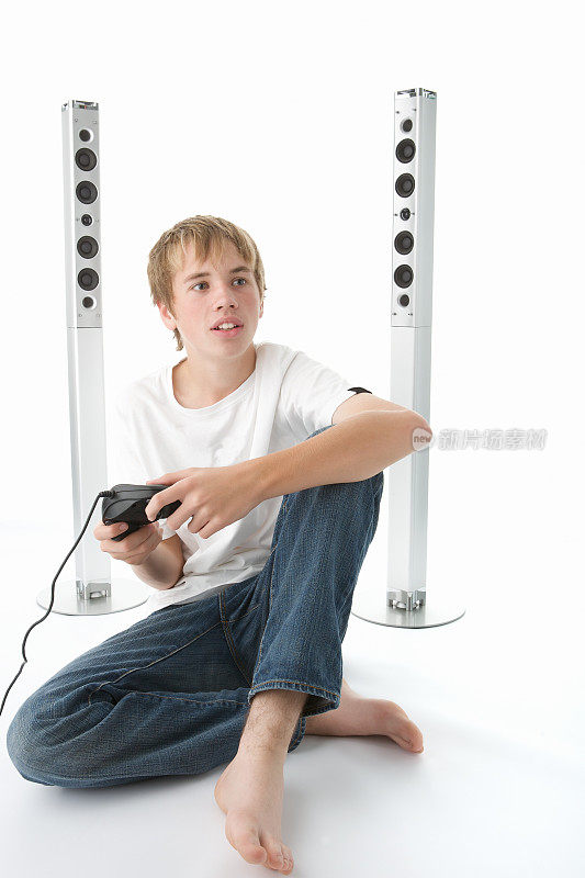 十几岁的男孩盘腿坐在地板上玩电子游戏