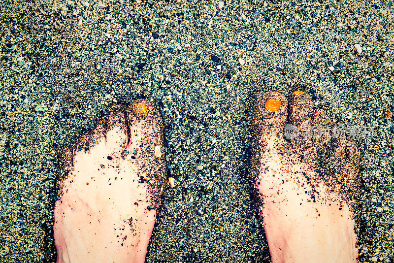 女性的一部分脚踩在沙子上