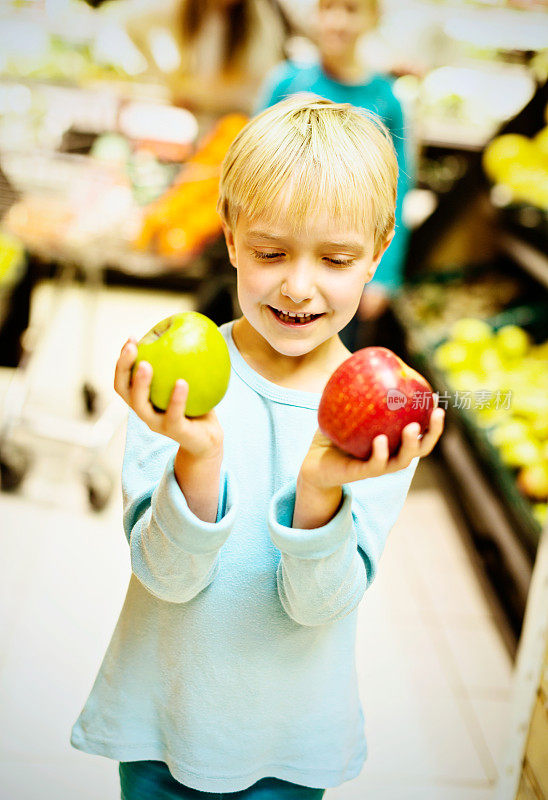 红色还是绿色?小女孩在超市挑选苹果