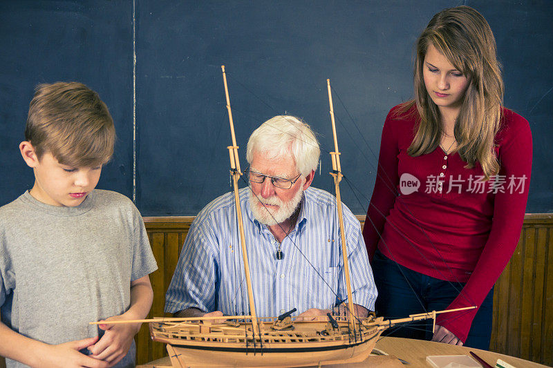 学生们在教室里看一个造船模型