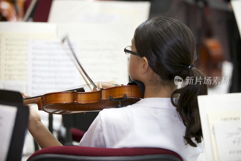 年轻的小提琴家小女孩在管弦乐队演奏。