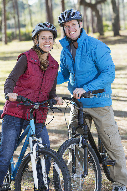 一对夫妇在寒冷的秋日在公园里骑自行车