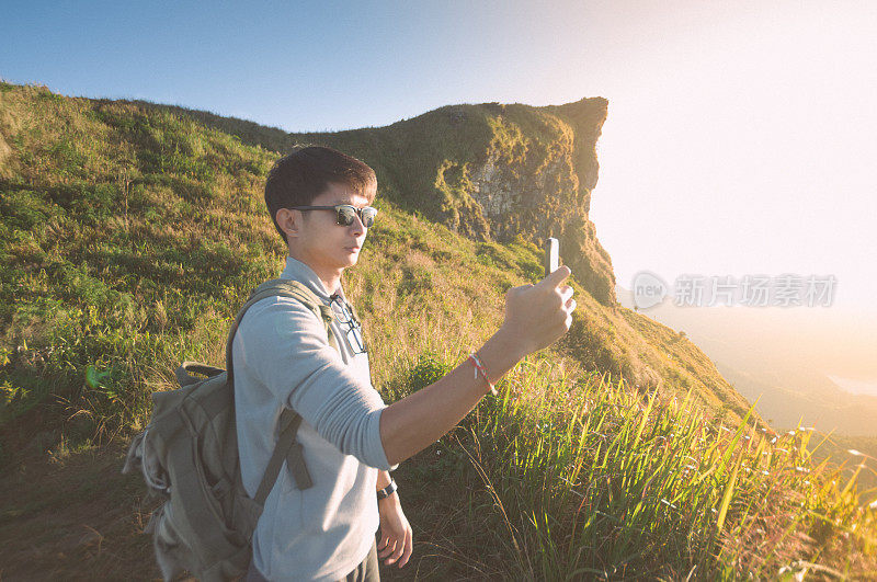 年轻的旅行者站在山上望着夕阳。