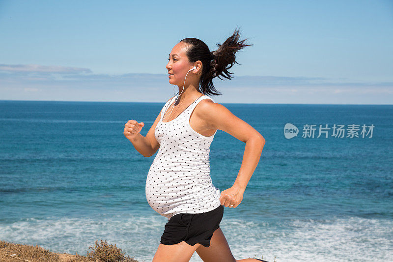 美丽的孕妇沿着海岸慢跑以保持健康