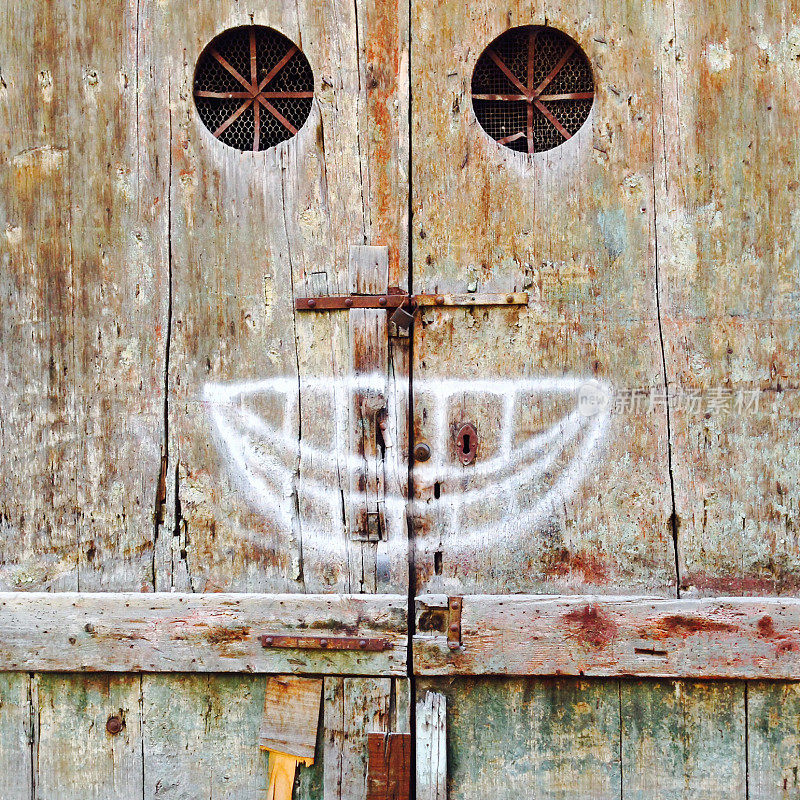 拟人化的脸在一个木制的入口门上涂鸦