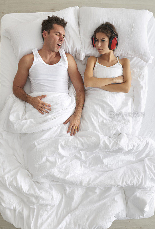 男人在床上打鼾，女人戴着护耳器