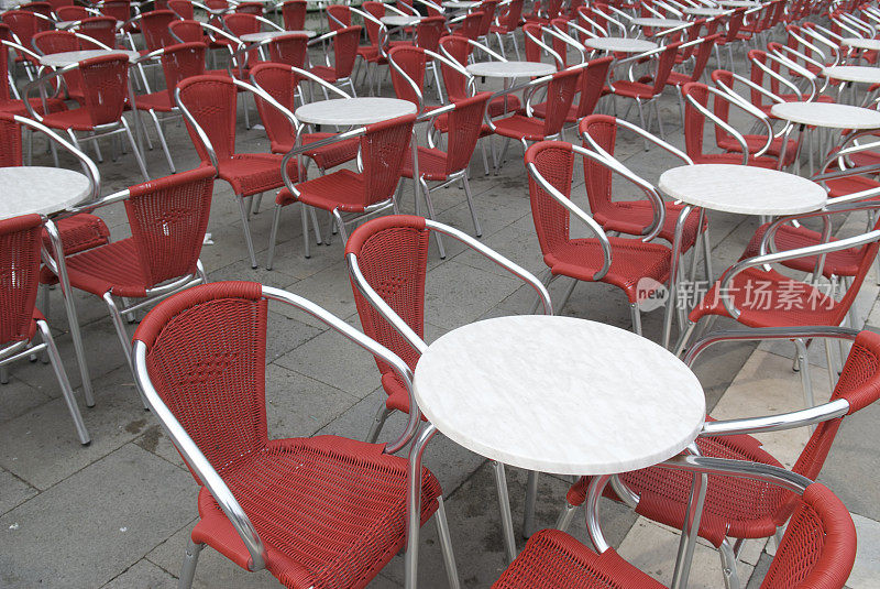 意大利威尼斯户外咖啡馆，红椅子排着空桌子
