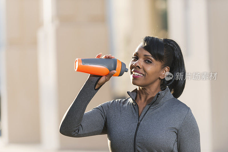 一位黑人妇女喝着运动水壶里的水