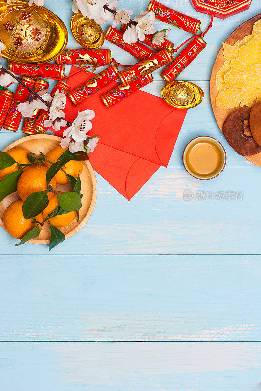 农历新年。鞭炮、中国金元宝、传统红包以及木质背景上的鲜橙装饰