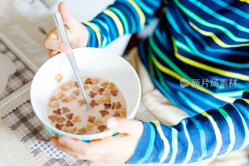 小男孩的手特写吃自制的麦片早餐或午餐