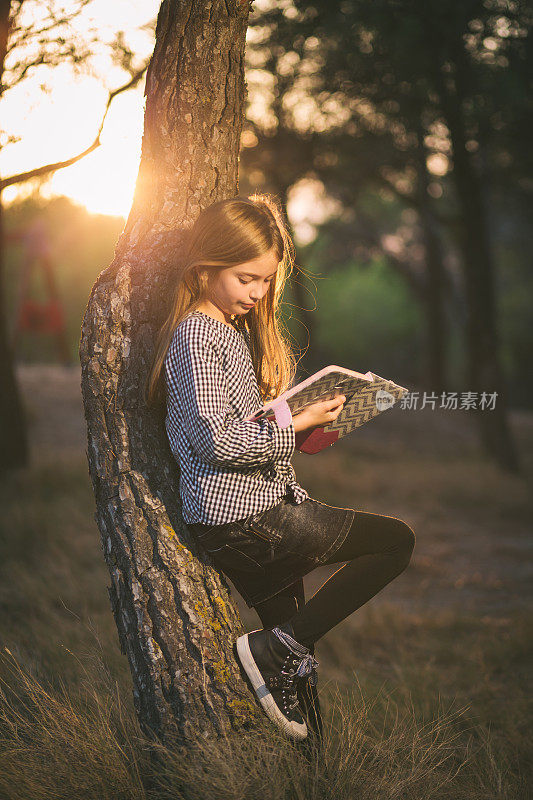 一个可爱的小女孩玩平板电脑的户外肖像。