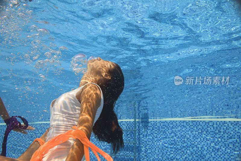 水下时尚泳池派对，年轻女子在游泳池跳水