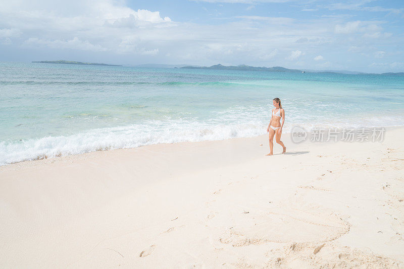 在菲律宾热带气候的热带海滩上行走的女人