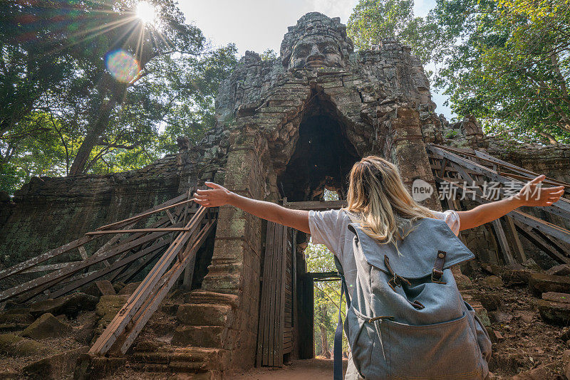 女旅人从寺庙的复杂大门伸出双臂，感受着旅行的自由和幸福