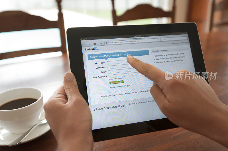 一个女人拿着ipad，屏幕上显示着Linkedin的登录界面。