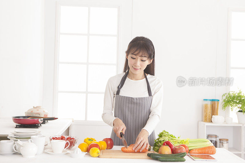 年轻女人在厨房切红萝卜