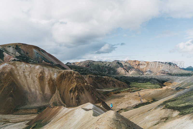 在冰岛的Landmannalaugar，一名妇女在彩色山脉附近徒步旅行