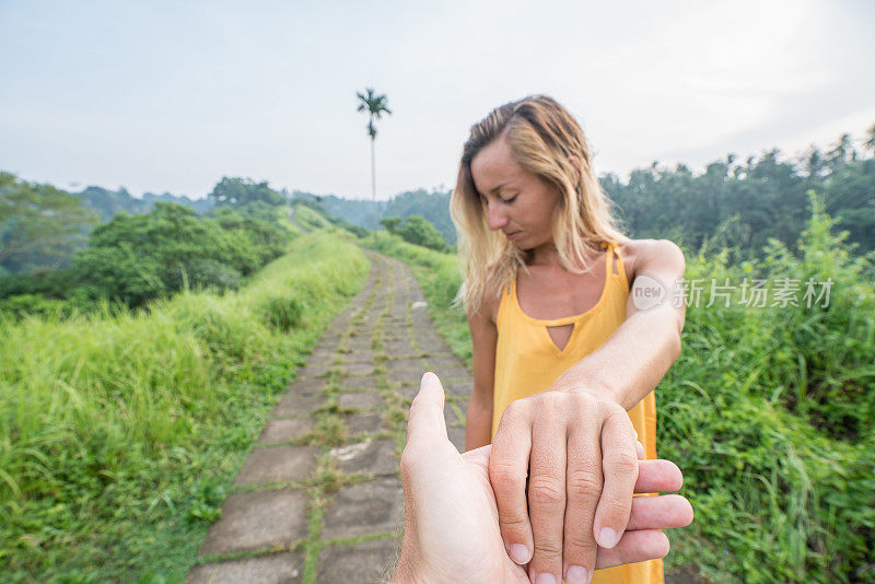 跟随我的概念年轻女子带领男友到稻田在Campuhan岭漫步在巴厘岛，亚洲人旅游奇迹分享爱的概念-
