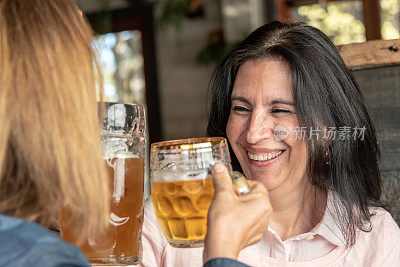 微笑的成熟女人用啤酒敬酒