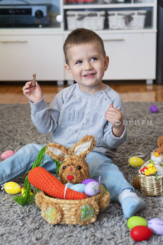 小男孩坐在地板上吃巧克力庆祝复活节
