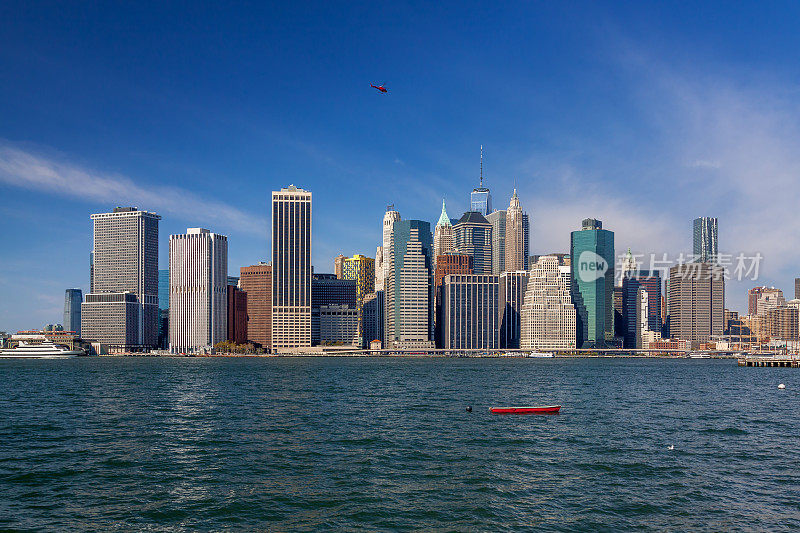 纽约城市天际线与金融区曼哈顿下东区和红划艇停泊在东河，纽约，美国。
