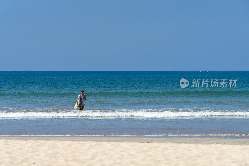 一个年轻人带着冲浪板离开帕卡朗海滩