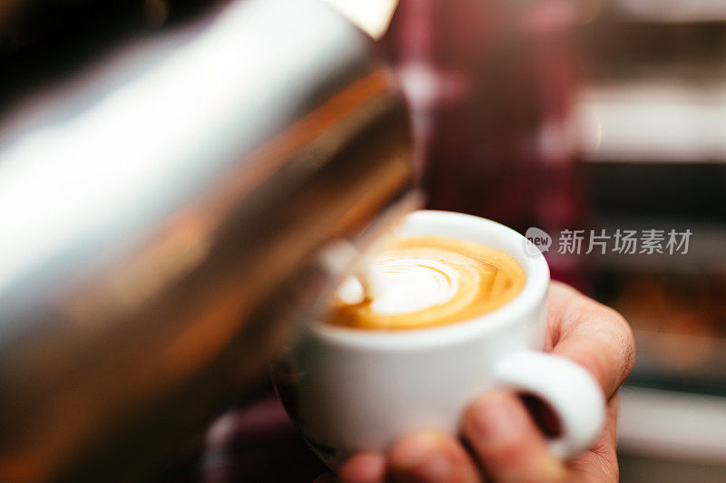 咖啡师将牛奶倒入咖啡中，制作拉花艺术