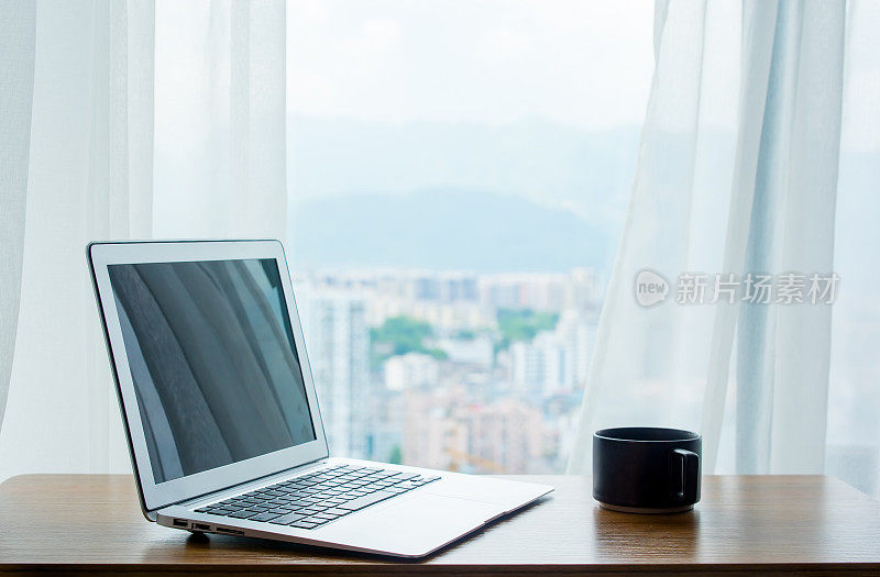 笔记本电脑放在靠窗的桌子上