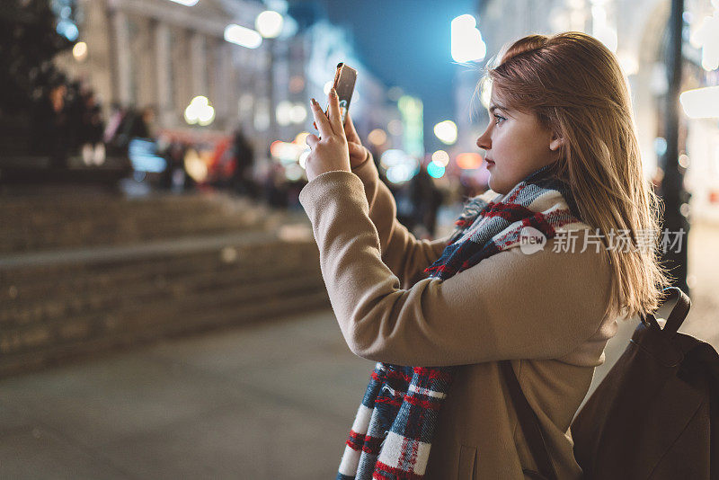 黄昏时分，年轻女子在皮卡迪利广场拍照