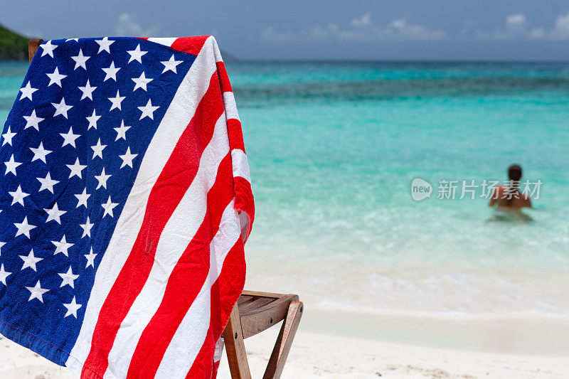 美国国旗毛巾在椅子上与女人在维尔京群岛热带海滩