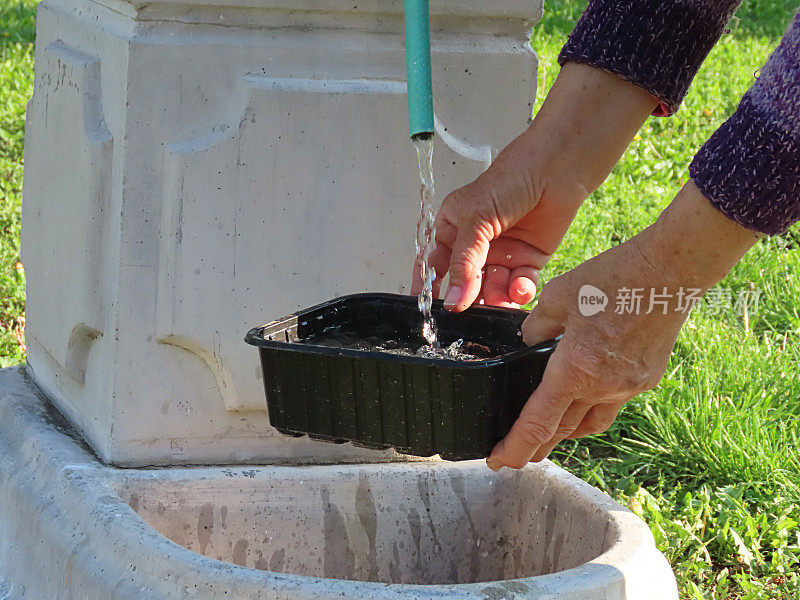 一个老妇人在后院用水龙头