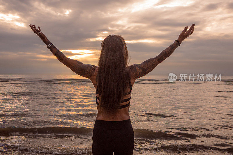 在海滩锻炼期间的纹身资深女性