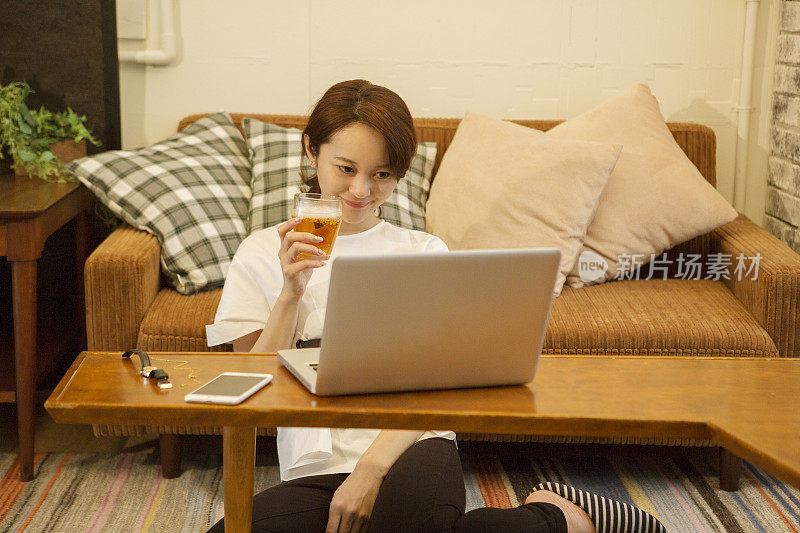 中年女人在客厅喝啤酒，用笔记本电脑