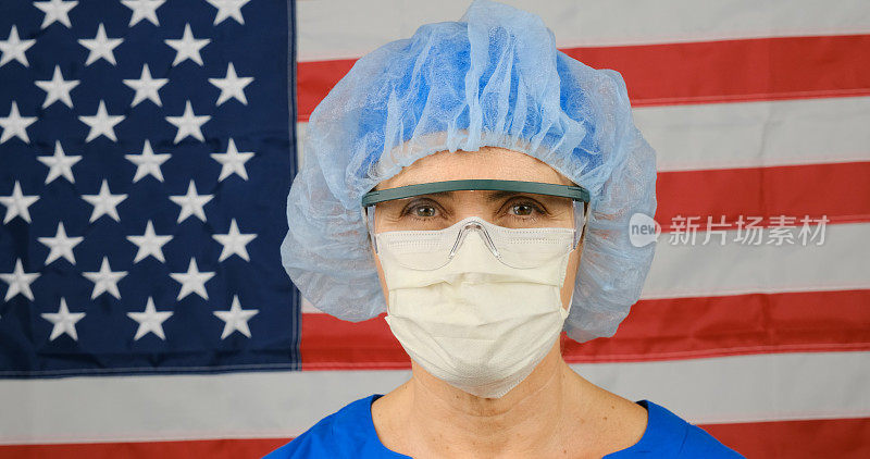 劳累过度，在一天紧张工作后戴着防护眼镜和面具的成熟女性医护人员，背景是美国国旗